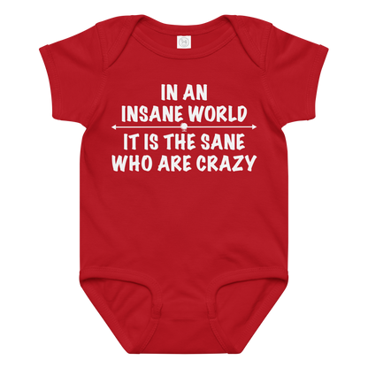 "In an insane world, it is the sane who are crazy" printed on a red baby jersey bodysuit laying on a flat surface amongst other clothes