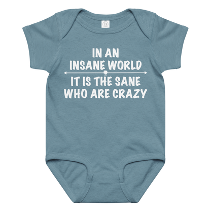 "In an insane world, it is the sane who are crazy" printed on a vintage indigo baby jersey bodysuit laying on a flat surface amongst other clothes