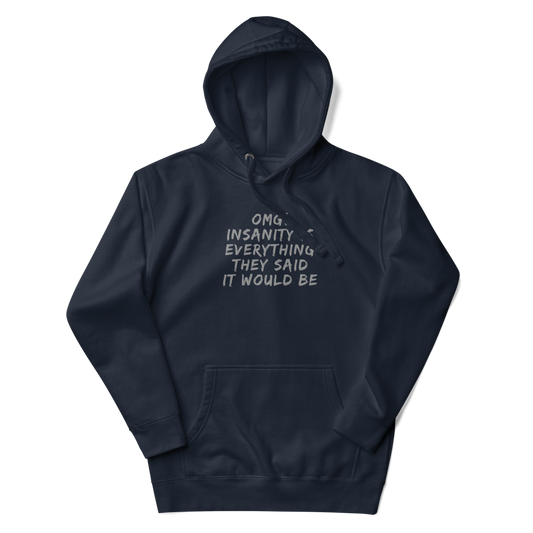 "OMG! Insanity is everything they said it would be" printed on a navy blazer unisex hoodie laying on a flat surface with the hood up