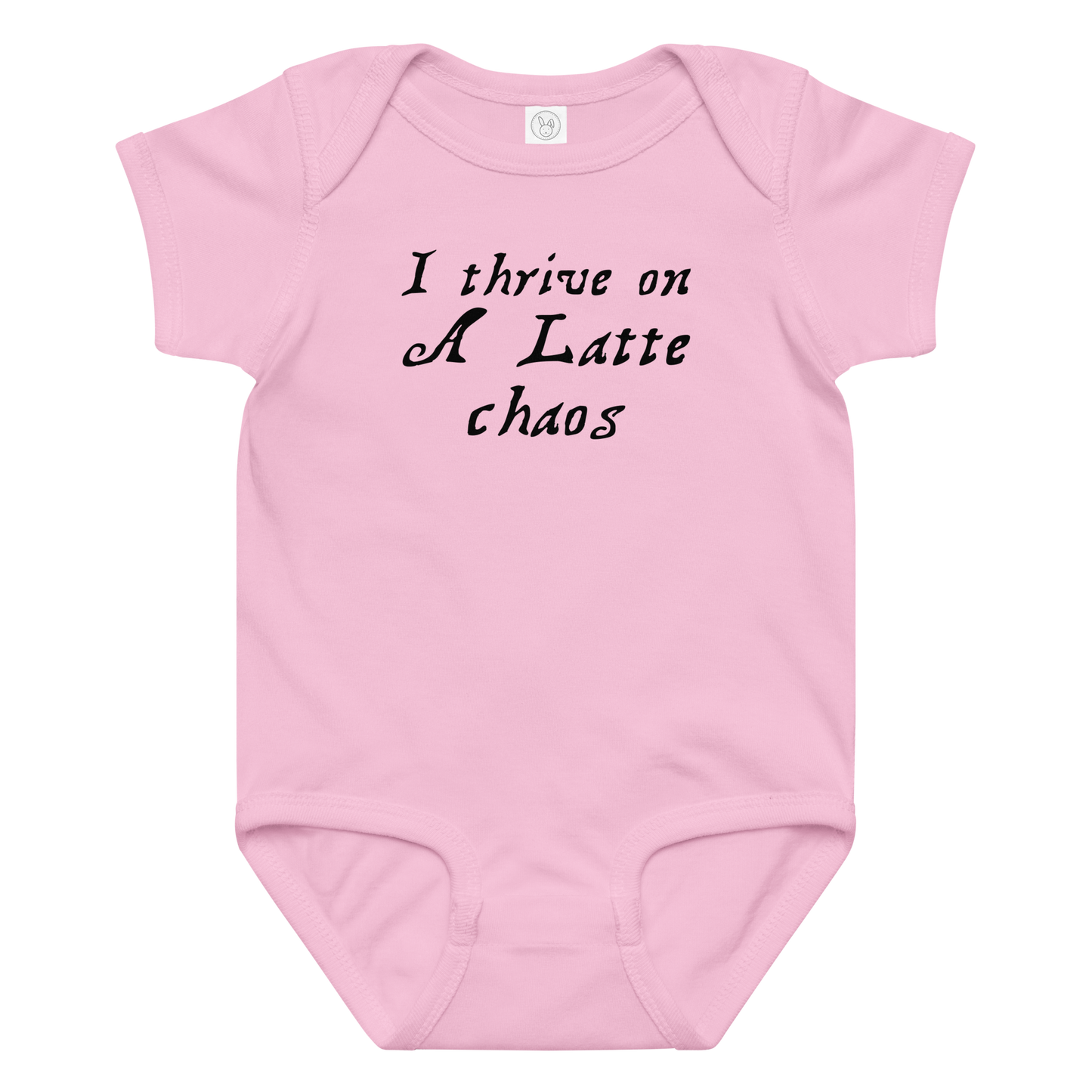 "I thrive on a latte chaos" printed on a pink baby jersey bodysuit laying on a flat surface amongst other clothes