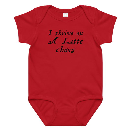 "I thrive on a latte chaos" printed on a red baby jersey bodysuit laying on a flat surface amongst other clothes