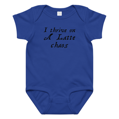 "I thrive on a latte chaos" printed on a royal baby jersey bodysuit laying on a flat surface amongst other clothes