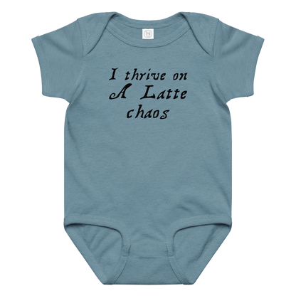 "I thrive on a latte chaos" printed on a vintage indigo baby jersey bodysuit laying on a flat surface amongst other clothes
