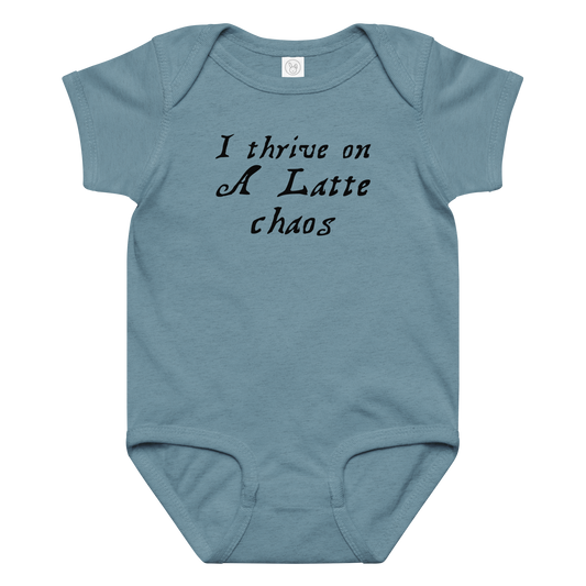 "I thrive on a latte chaos" printed on a vintage indigo baby jersey bodysuit laying on a flat surface amongst other clothes