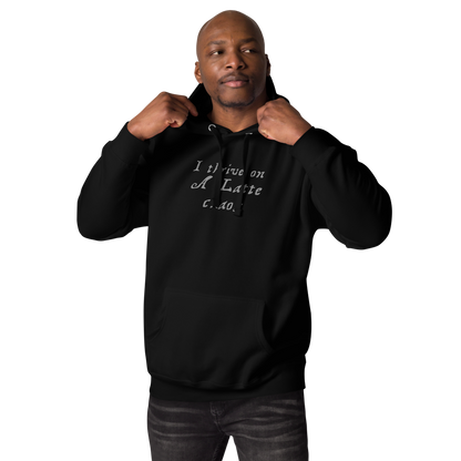 "I thrive on a latte chaos" printed on a black unisex hoodie worn by a male