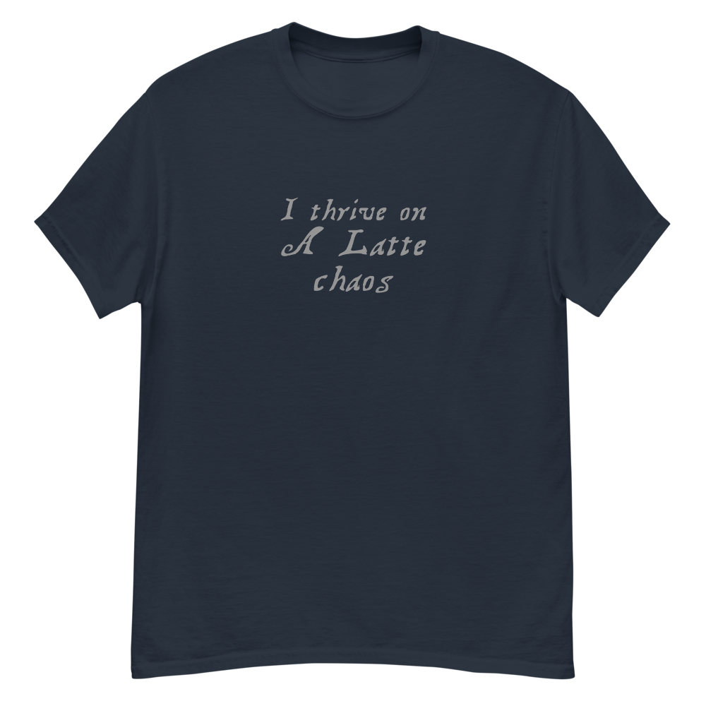 "I thrive on a latte chaos" printed on a navy unisex classic tee laying on a flat surface