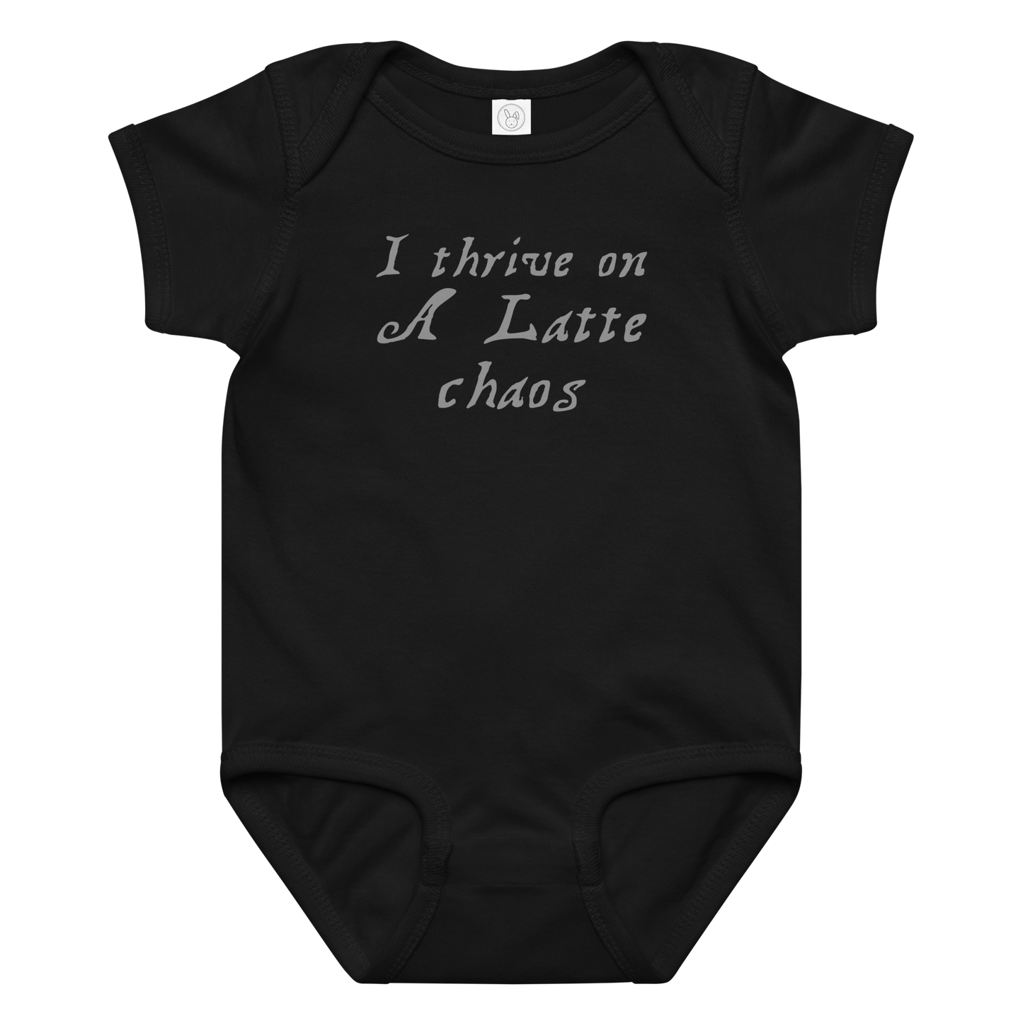 "I thrive on a latte chaos" printed on a black baby jersey bodysuit laying on a flat surface amongst other clothes