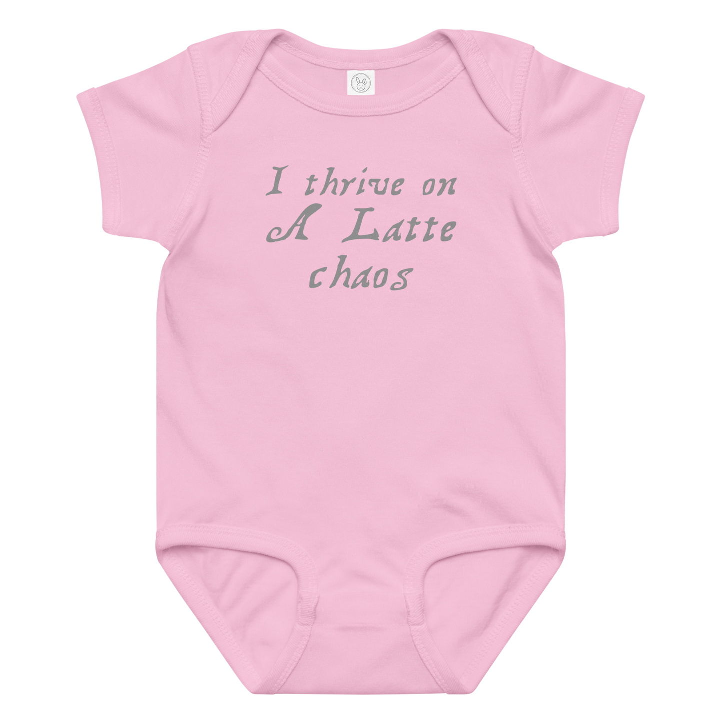 "I thrive on a latte chaos" printed on a pink baby jersey bodysuit laying on a flat surface amongst other clothes