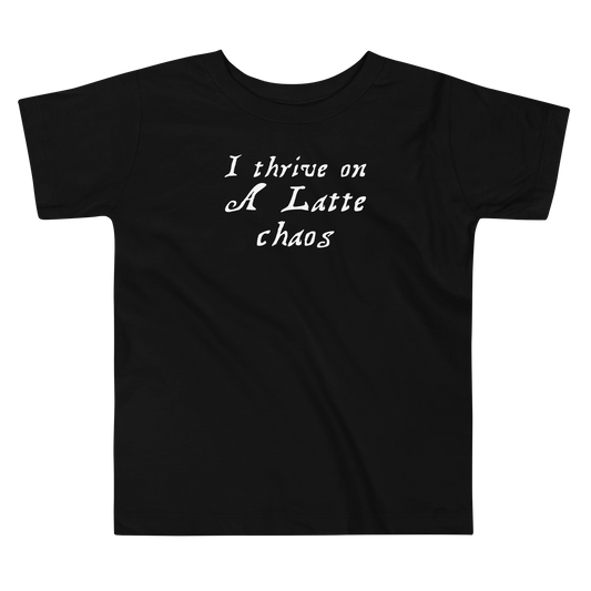 "I thrive on a latte chaos" printed on a black toddler short sleeve tee laying on a flat surface