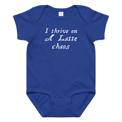 "I thrive on a latte chaos" printed on a royal baby jersey bodysuit laying on a flat surface amongst other clothes