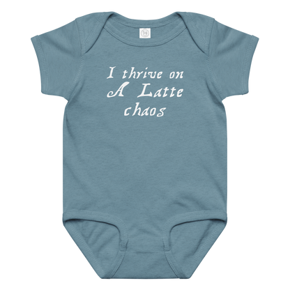 "I thrive on a latte chaos" printed on a vintage indigo baby jersey bodysuit laying on a flat surface amongst other clothes