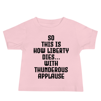 "So this is how liberty dies… with thunderous applause" printed on a pink baby jersey short sleeve tee laying on a flat surface