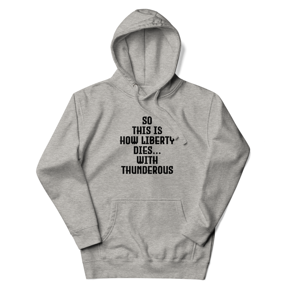 "So this is how liberty dies… with thunderous applause" printed on a carbon grey unisex hoodie laying on a flat surface with the hood up