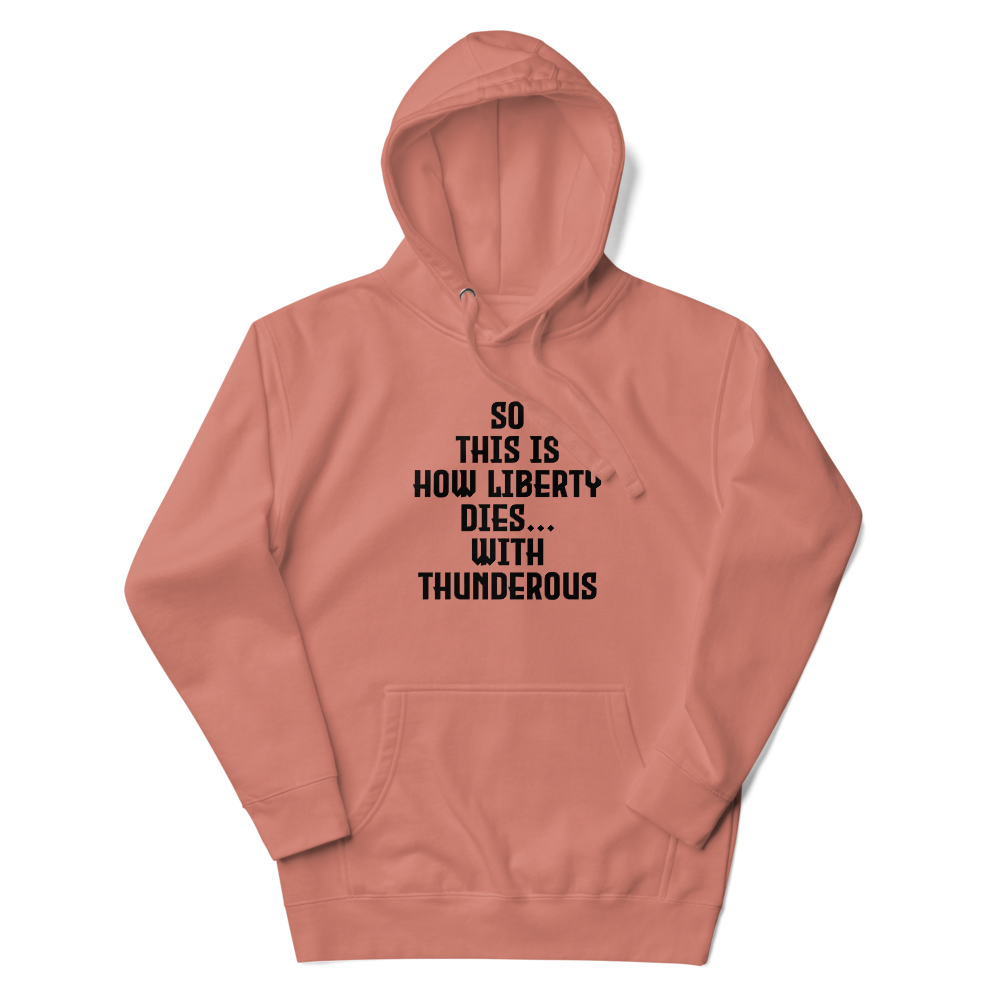 "So this is how liberty dies… with thunderous applause" printed on a dusty rose unisex hoodie laying on a flat surface with the hood up