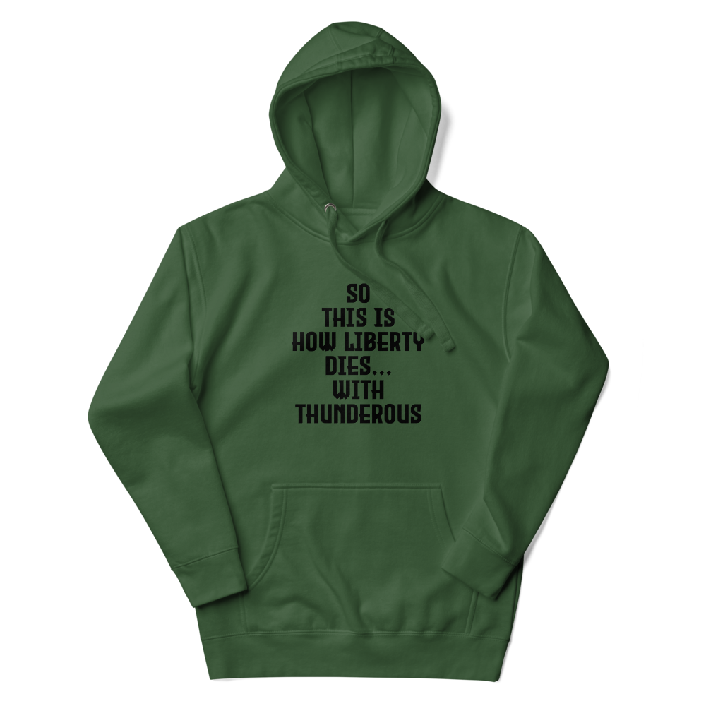 "So this is how liberty dies… with thunderous applause" printed on a forest green unisex hoodie laying on a flat surface with the hood up
