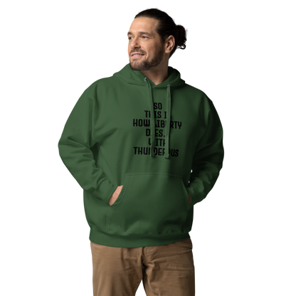 "So this is how liberty dies… with thunderous applause" printed on a forest green unisex hoodie worn by a male