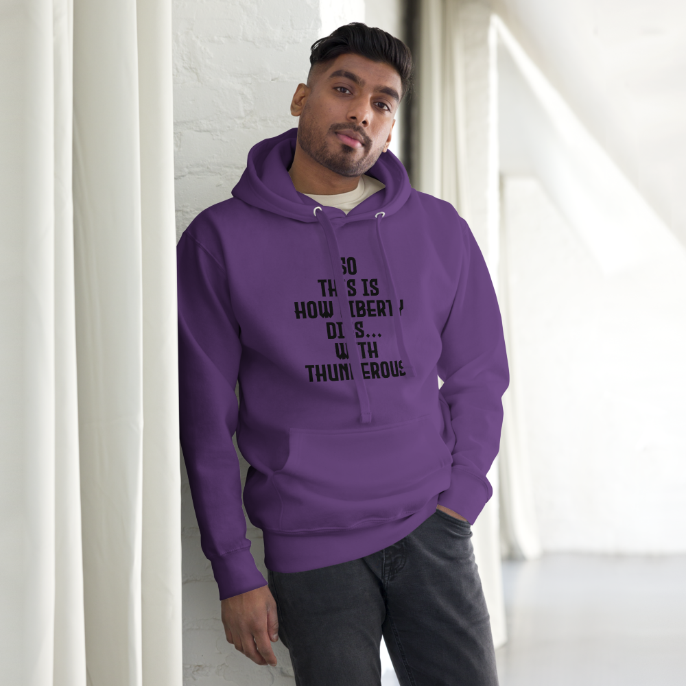 "So this is how liberty dies… with thunderous applause" printed on a purple unisex hoodie worn by a male