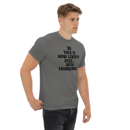 "So this is how liberty dies… with thunderous applause" printed on a charcoal unisex classic tee worn by a male