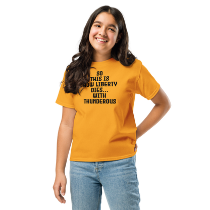 "So this is how liberty dies… with thunderous applause" printed on a gold youth classic tee worn by a female