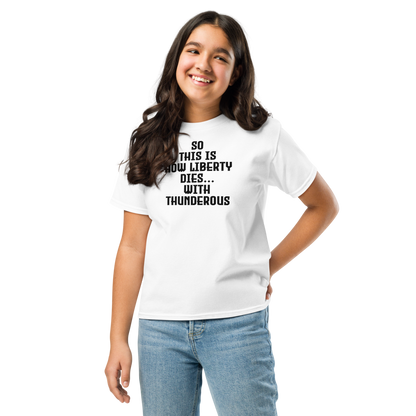 "So this is how liberty dies… with thunderous applause" printed on a white youth classic tee worn by a female