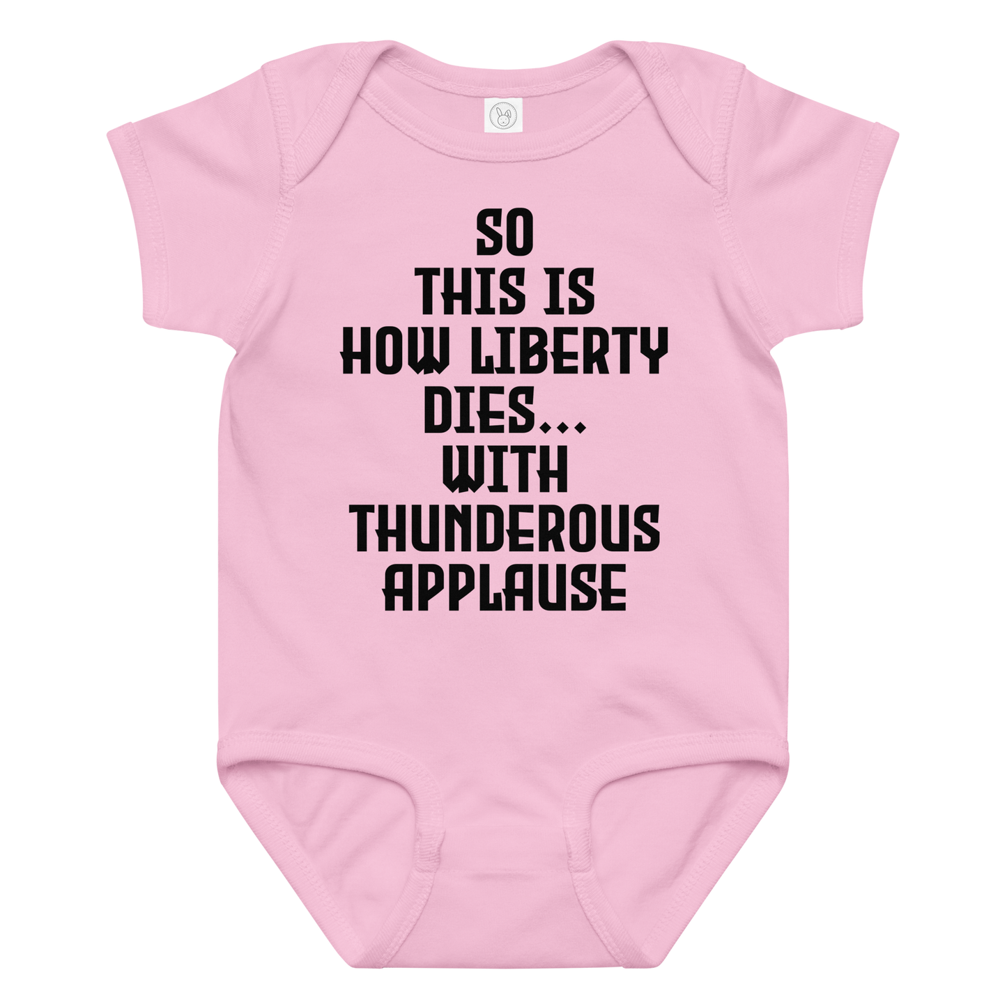"So this is how liberty dies… with thunderous applause" printed on a pink baby jersey bodysuit laying on a flat surface amongst other clothes
