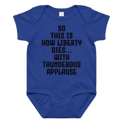 "So this is how liberty dies… with thunderous applause" printed on a royal baby jersey bodysuit laying on a flat surface amongst other clothes