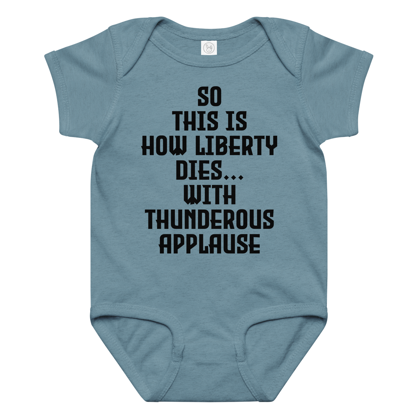 "So this is how liberty dies… with thunderous applause" printed on a vintage indigo baby jersey bodysuit laying on a flat surface amongst other clothes