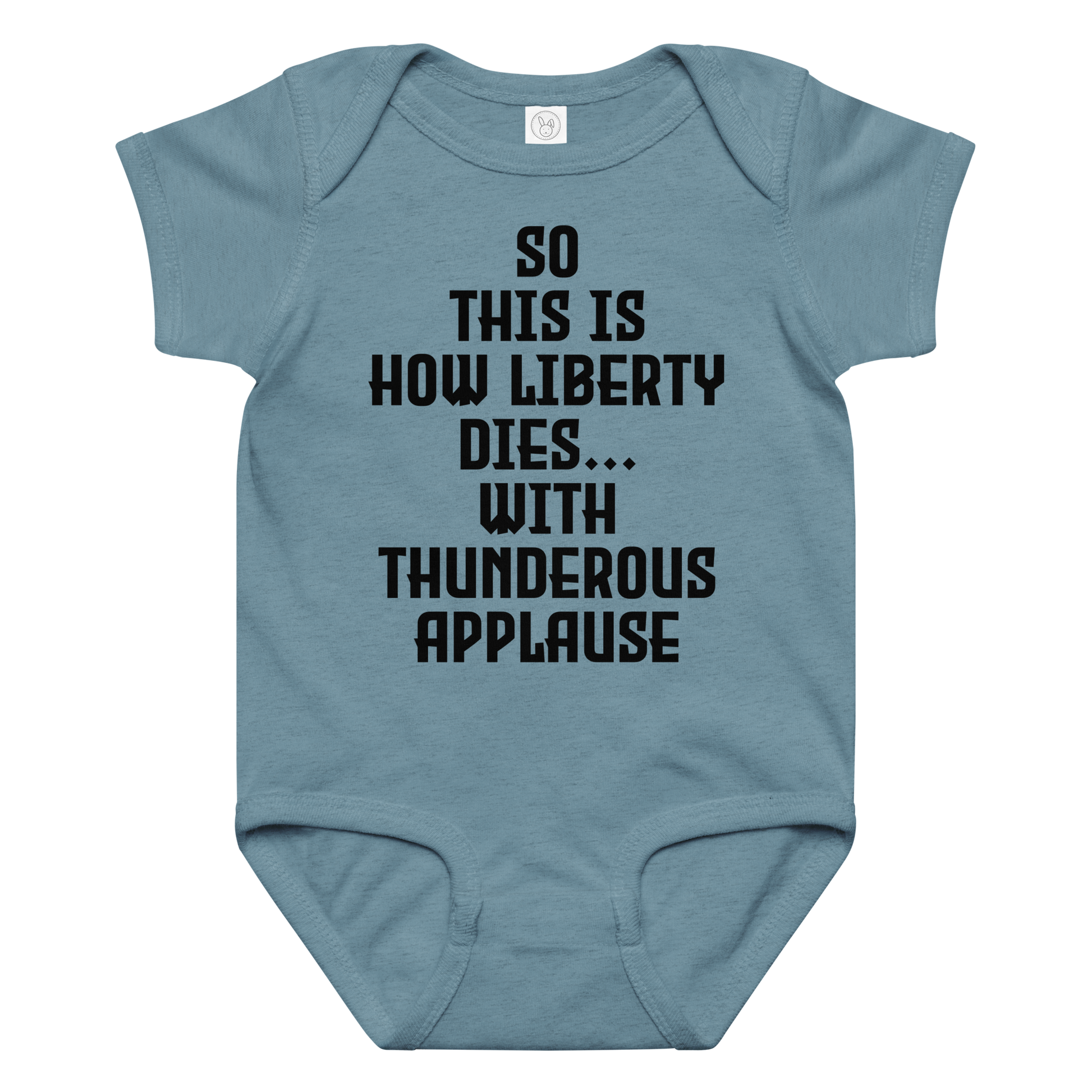 "So this is how liberty dies… with thunderous applause" printed on a vintage indigo baby jersey bodysuit laying on a flat surface amongst other clothes