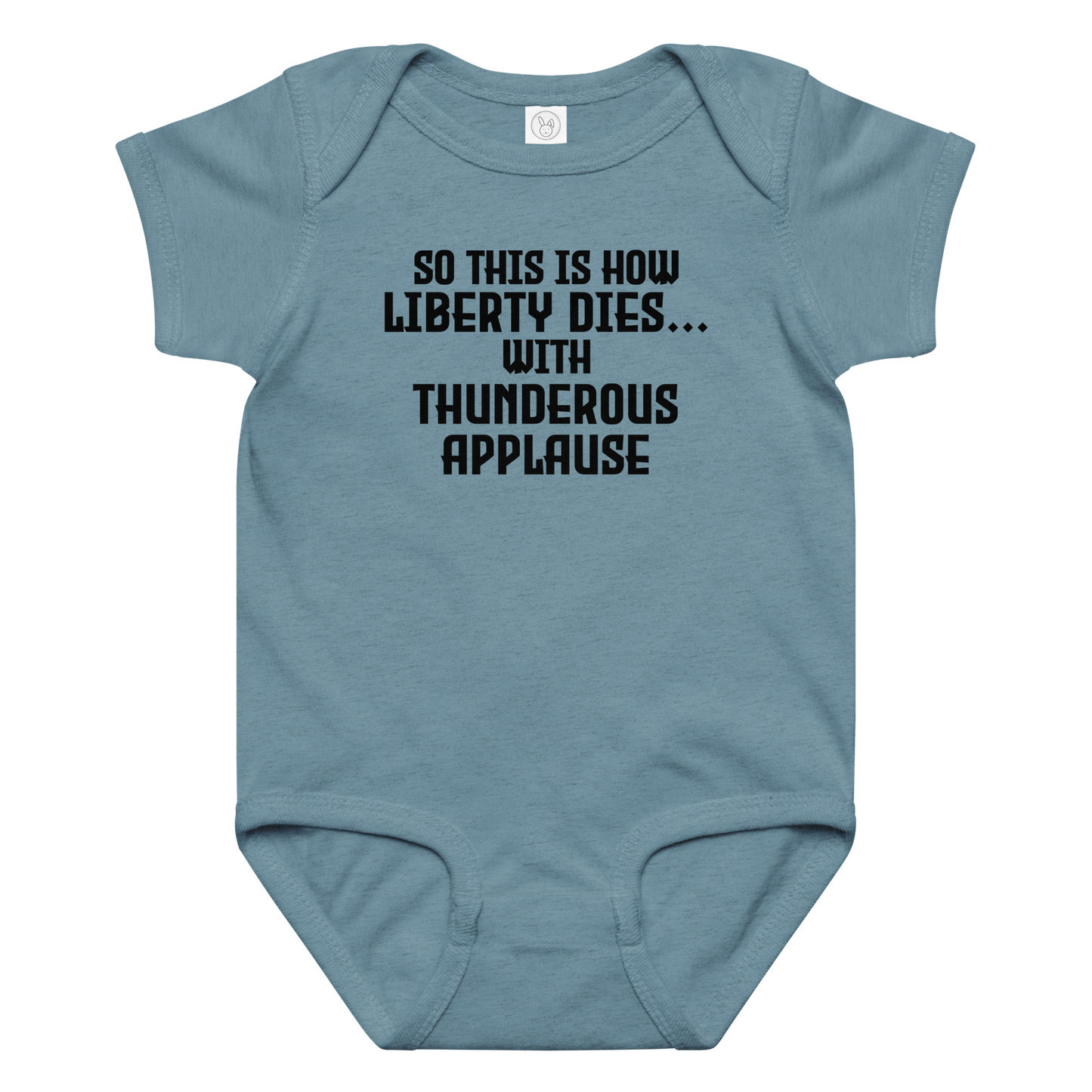 "So this is how liberty dies… with thunderous applause" printed on a vintage indigo baby jersey bodysuit laying on a flat surface amongst other clothes