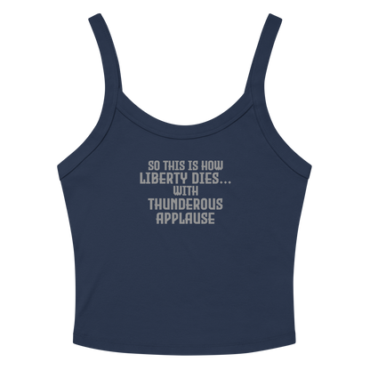 "So this is how liberty dies… with thunderous applause" printed on a solid navy blend women's micro-rib tanktop laying on a flat surface amongst sunglasses and shorts