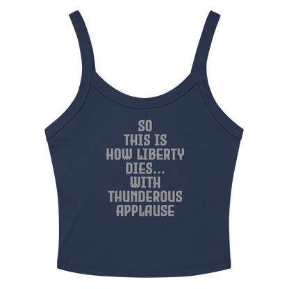 "So this is how liberty dies… with thunderous applause" printed on a solid navy blend women's micro-rib tanktop laying on a flat surface amongst sunglasses and shorts