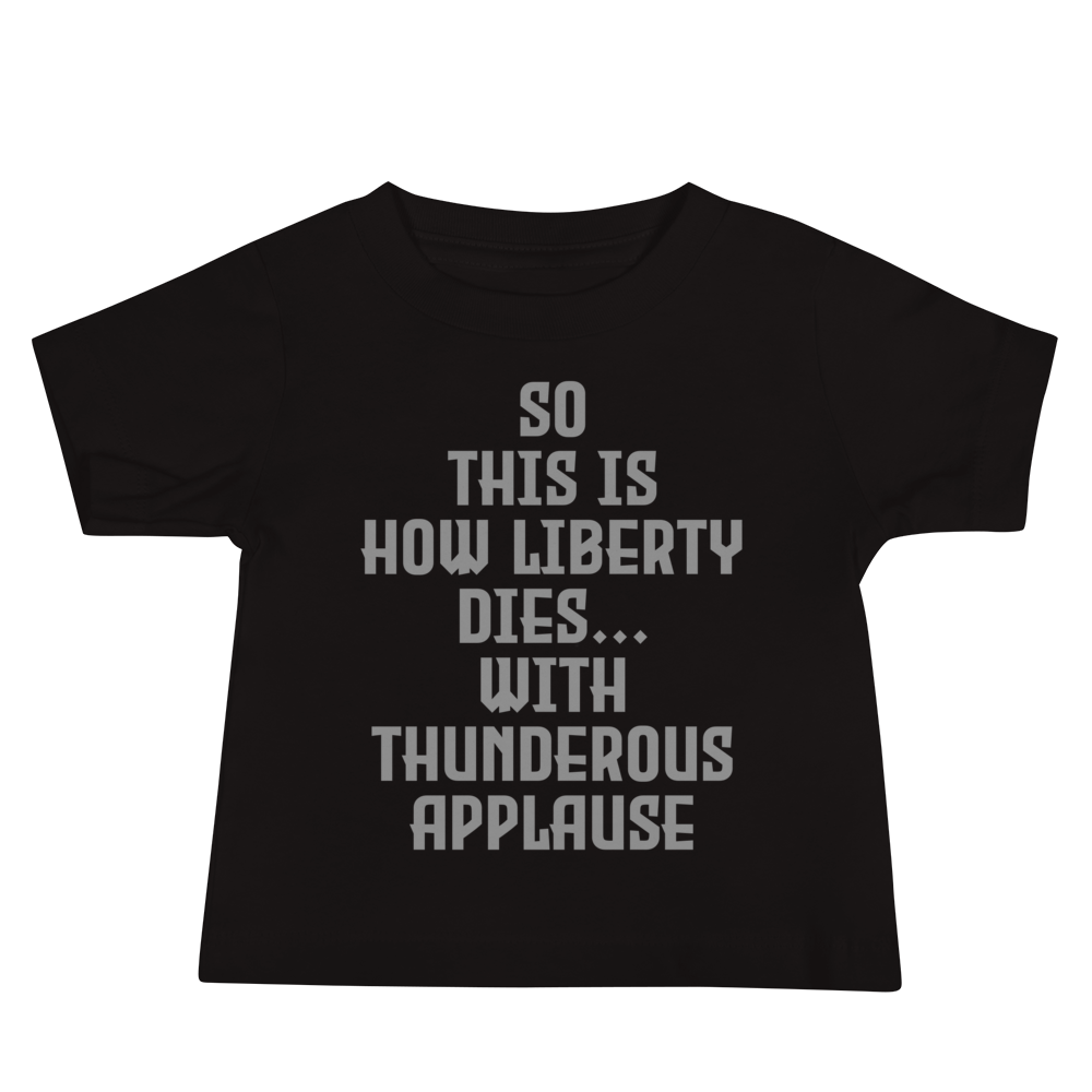 "So this is how liberty dies… with thunderous applause" printed on a black baby jersey short sleeve tee laying on a flat surface