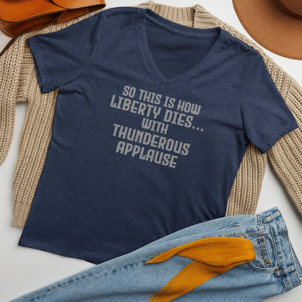 "So this is how liberty dies… with thunderous applause" printed on a heather navy women's relaxed v-neck t-shirt laying on a flat surface amongst other clothes