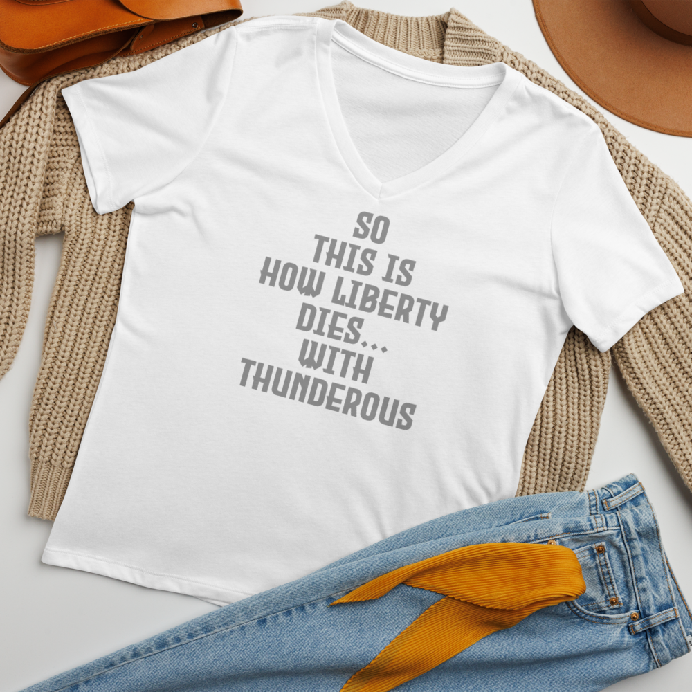 "So this is how liberty dies… with thunderous applause" printed on a solid white blend women's relaxed v-neck t-shirt laying on a flat surface amongst other clothes