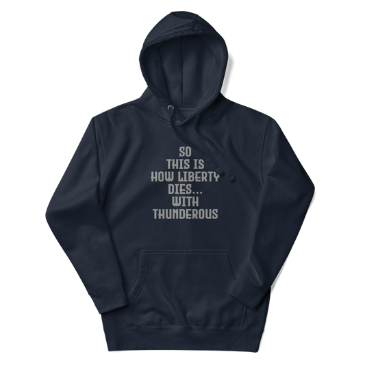 "So this is how liberty dies… with thunderous applause" printed on a navy blazer unisex hoodie laying on a flat surface with the hood up