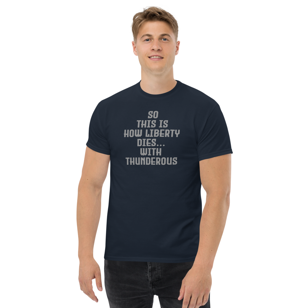 "So this is how liberty dies… with thunderous applause" printed on a navy unisex classic tee worn by a male