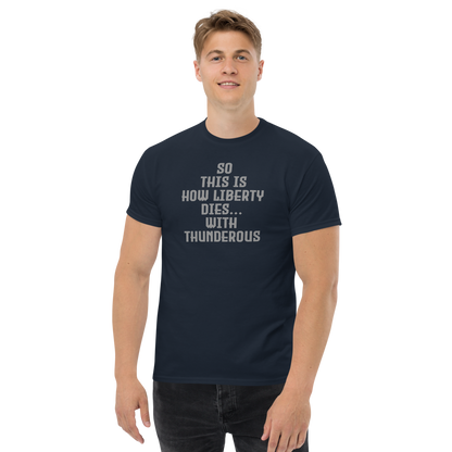 "So this is how liberty dies… with thunderous applause" printed on a navy unisex classic tee worn by a male