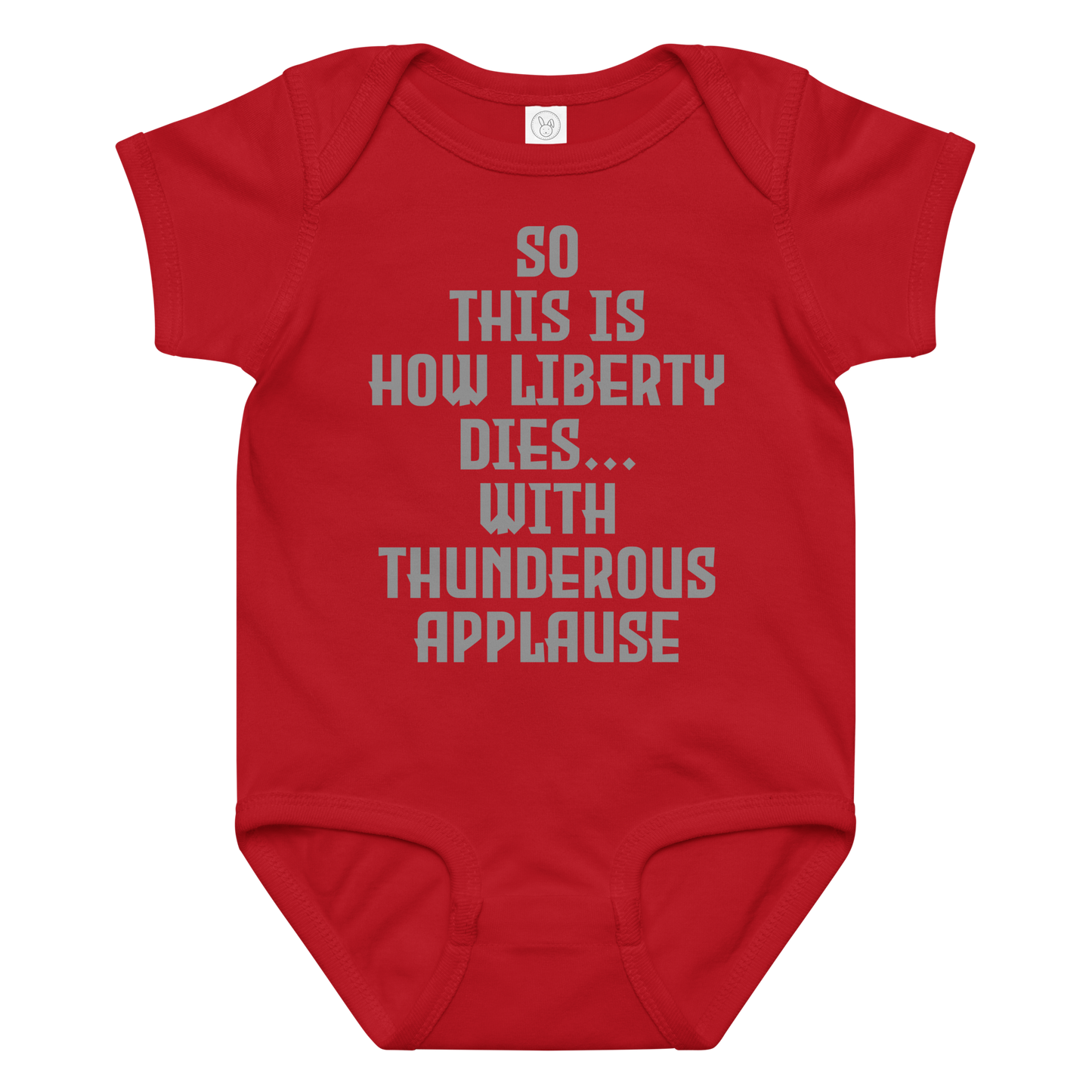 "So this is how liberty dies… with thunderous applause" printed on a red baby jersey bodysuit laying on a flat surface amongst other clothes