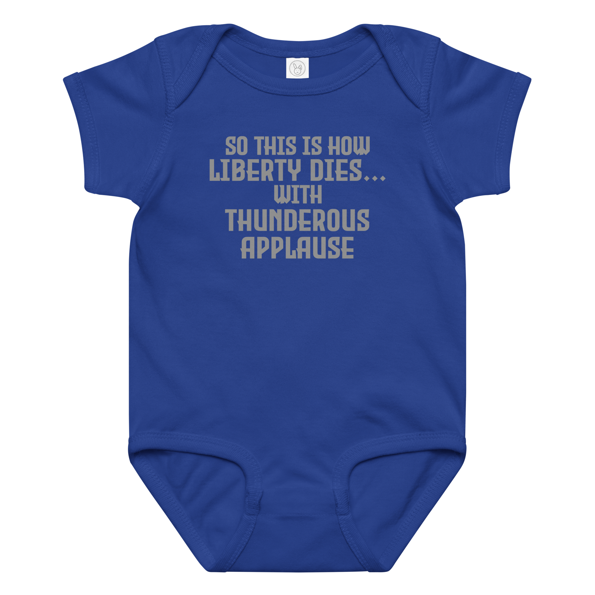 "So this is how liberty dies… with thunderous applause" printed on a royal baby jersey bodysuit laying on a flat surface amongst other clothes