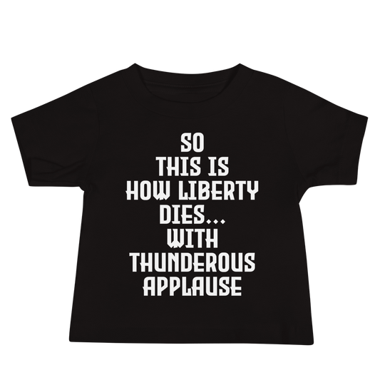 "So this is how liberty dies… with thunderous applause" printed on a black baby jersey short sleeve tee laying on a flat surface