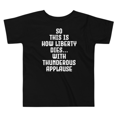 "So this is how liberty dies… with thunderous applause" printed on a black toddler short sleeve tee laying on a flat surface