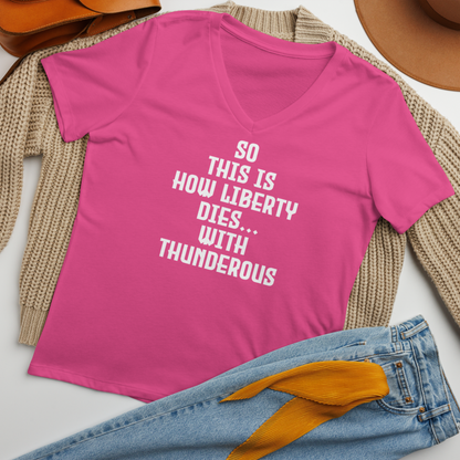 "So this is how liberty dies… with thunderous applause" printed on a berry women's relaxed v-neck t-shirt laying on a flat surface amongst other clothes