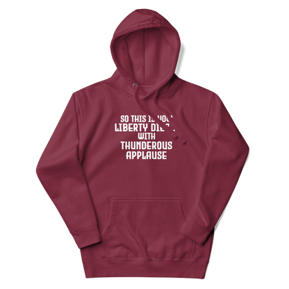 "So this is how liberty dies… with thunderous applause" printed on a maroon unisex hoodie laying on a flat surface with the hood up