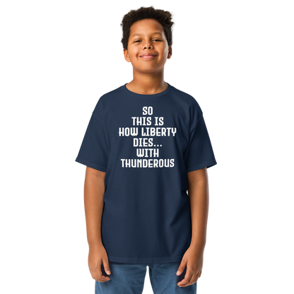"So this is how liberty dies… with thunderous applause" printed on a navy youth classic tee worn by a male
