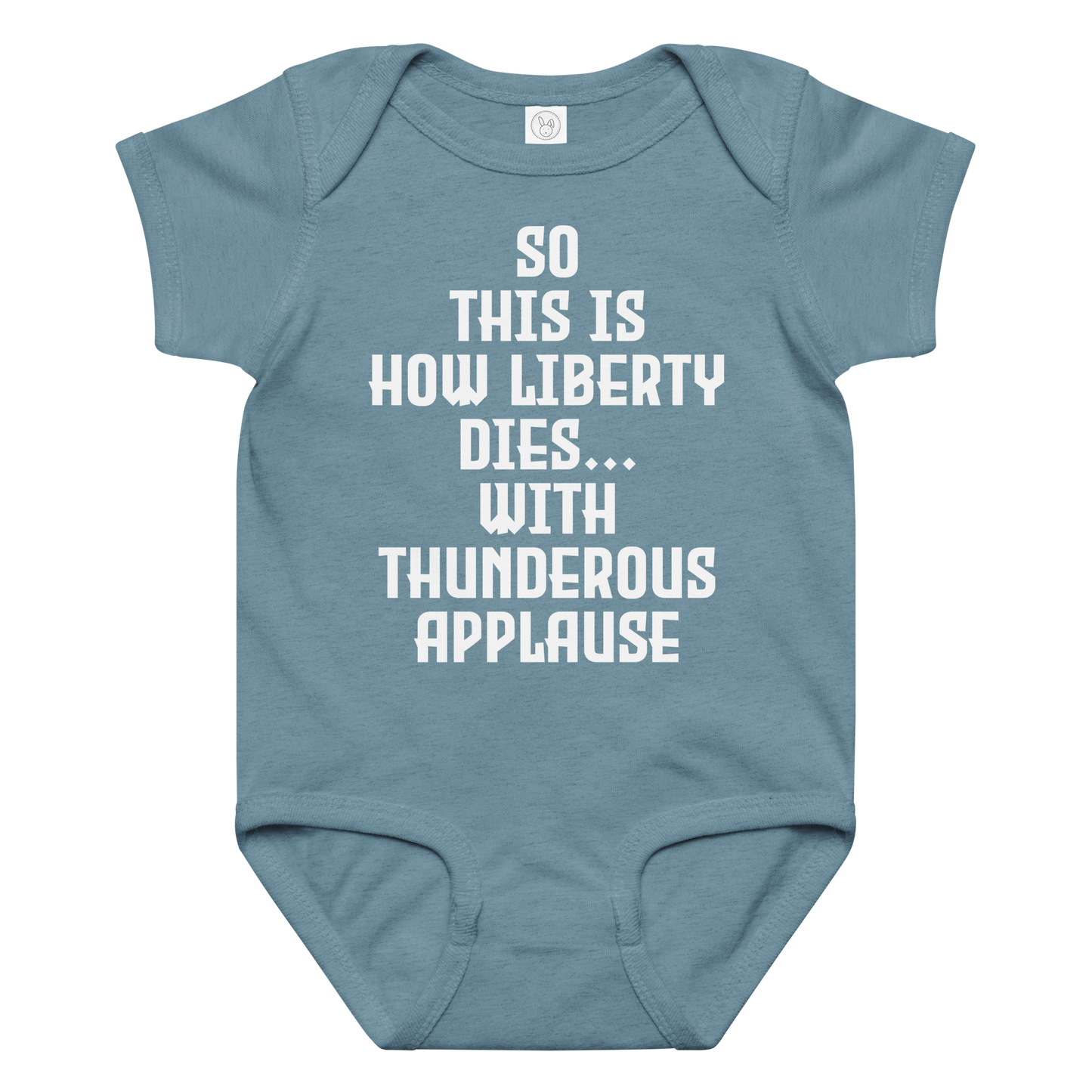 "So this is how liberty dies… with thunderous applause" printed on a vintage indigo baby jersey bodysuit laying on a flat surface amongst other clothes