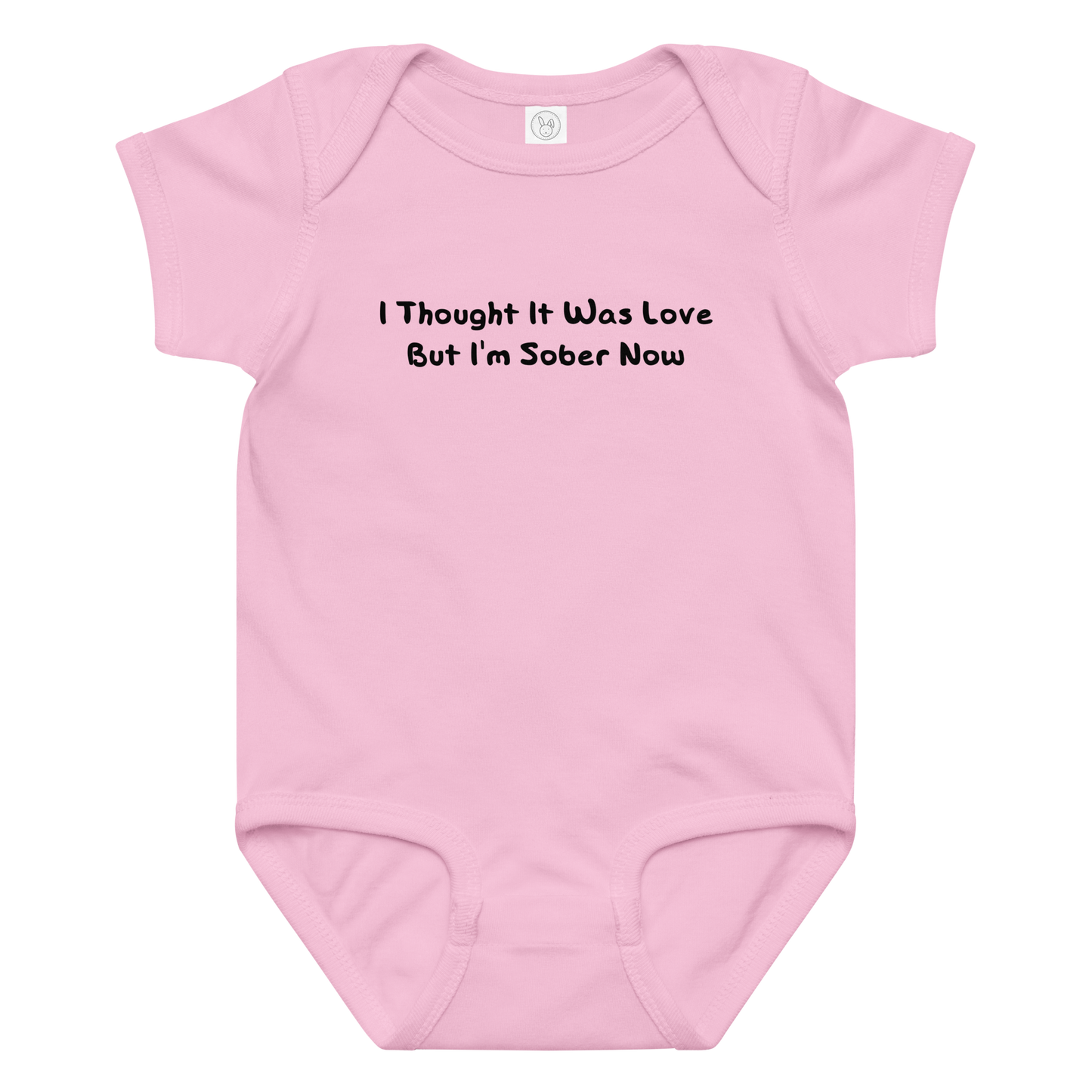 "I thought it was love but I’m sober now" printed on a pink baby jersey bodysuit laying on a flat surface amongst other clothes