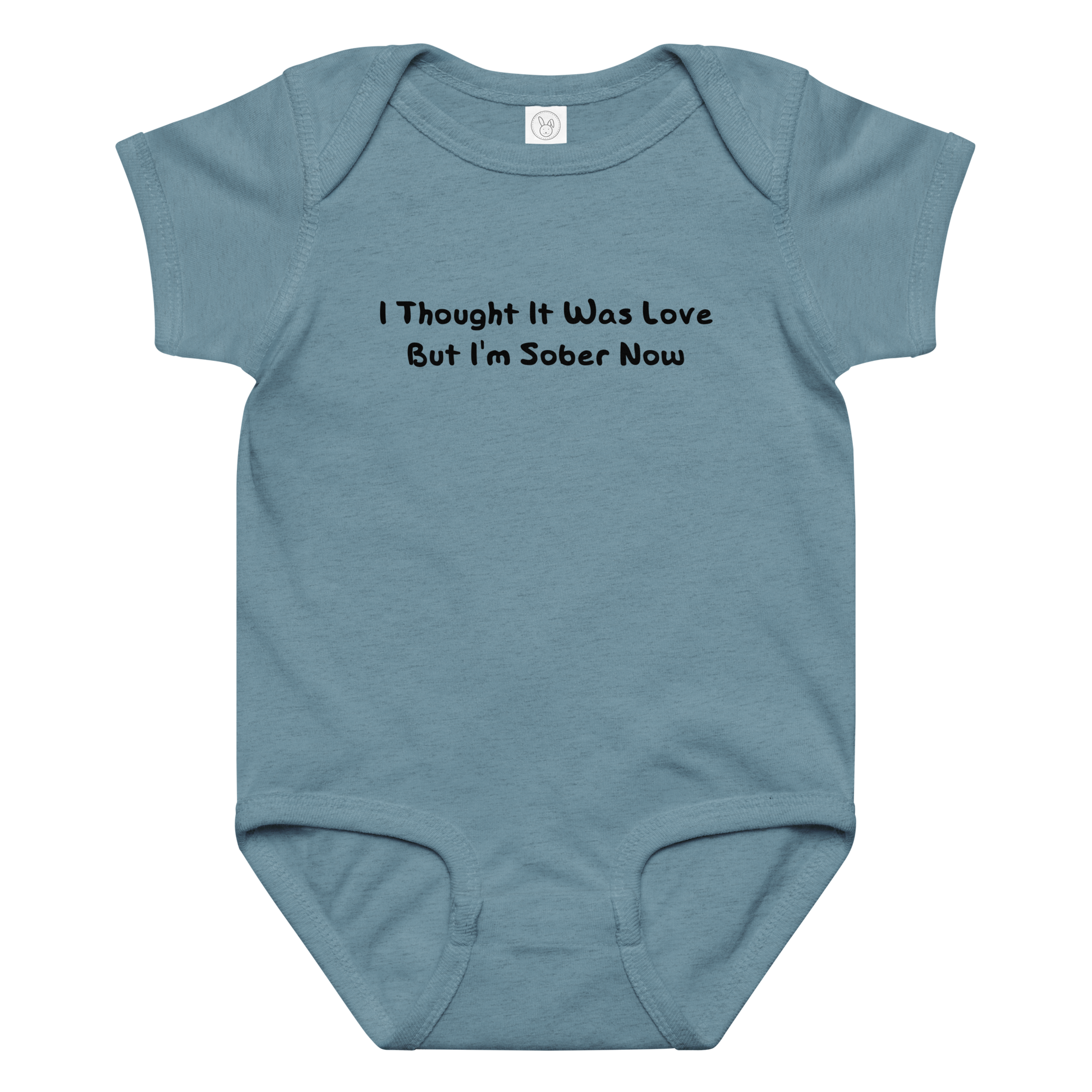 "I thought it was love but I’m sober now" printed on a vintage indigo baby jersey bodysuit laying on a flat surface amongst other clothes