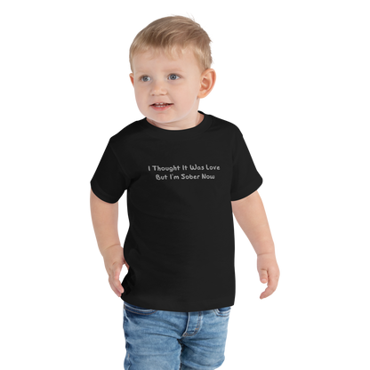 "I thought it was love but I’m sober now" printed on a black toddler short sleeve tee worn by a male