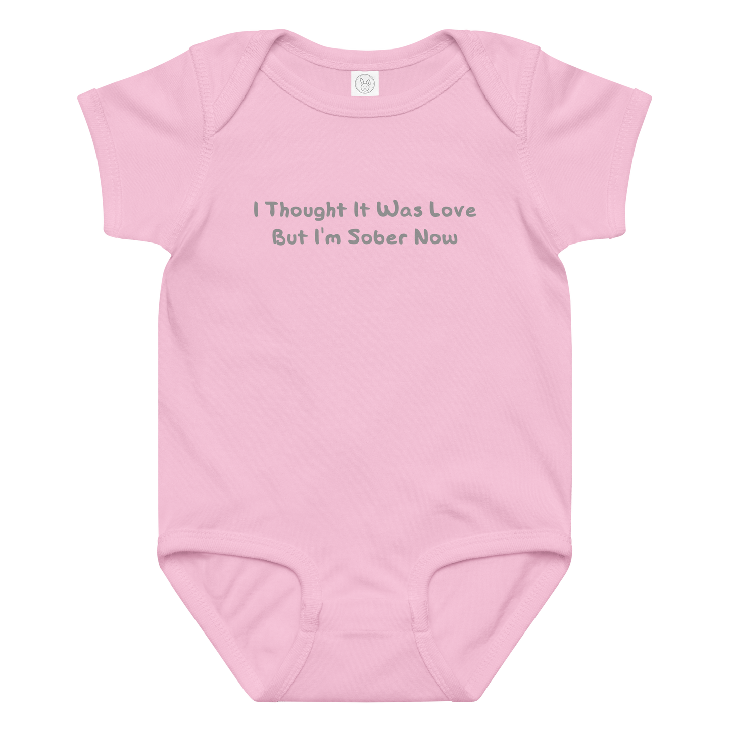 "I thought it was love but I’m sober now" printed on a pink baby jersey bodysuit laying on a flat surface amongst other clothes