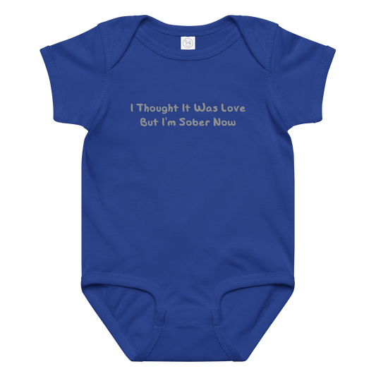 "I thought it was love but I’m sober now" printed on a royal baby jersey bodysuit laying on a flat surface amongst other clothes